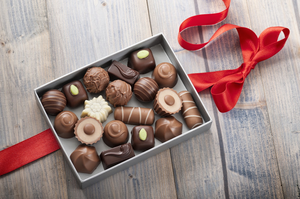 assorted chocolates confectionery in their gift box with red bow